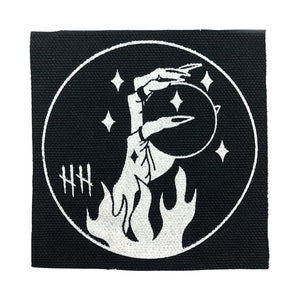 Black canvas patch, hand holding orb with flames and stars, hellhound jewelry patch