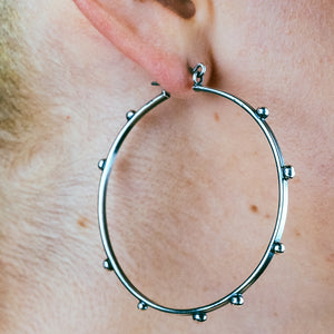 Studded silver hoop earrings. Model wearing silver hoop earrings. hellhound jewelry Hoop earrings.
